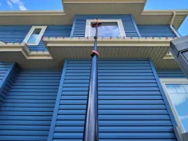 Technician washing windows on a two-story home